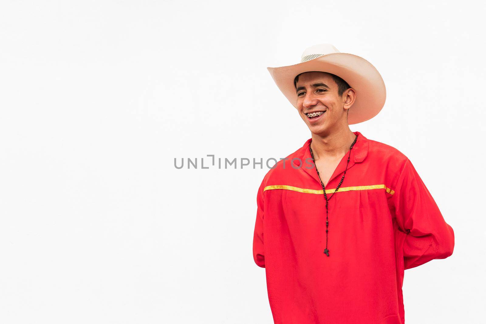 Latin teenager in the isolated white wall using traditional dress smiling