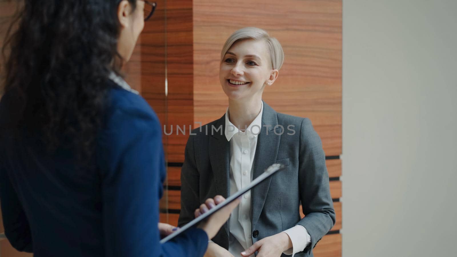 Two businesswomen colleagues talking in modern office indoors