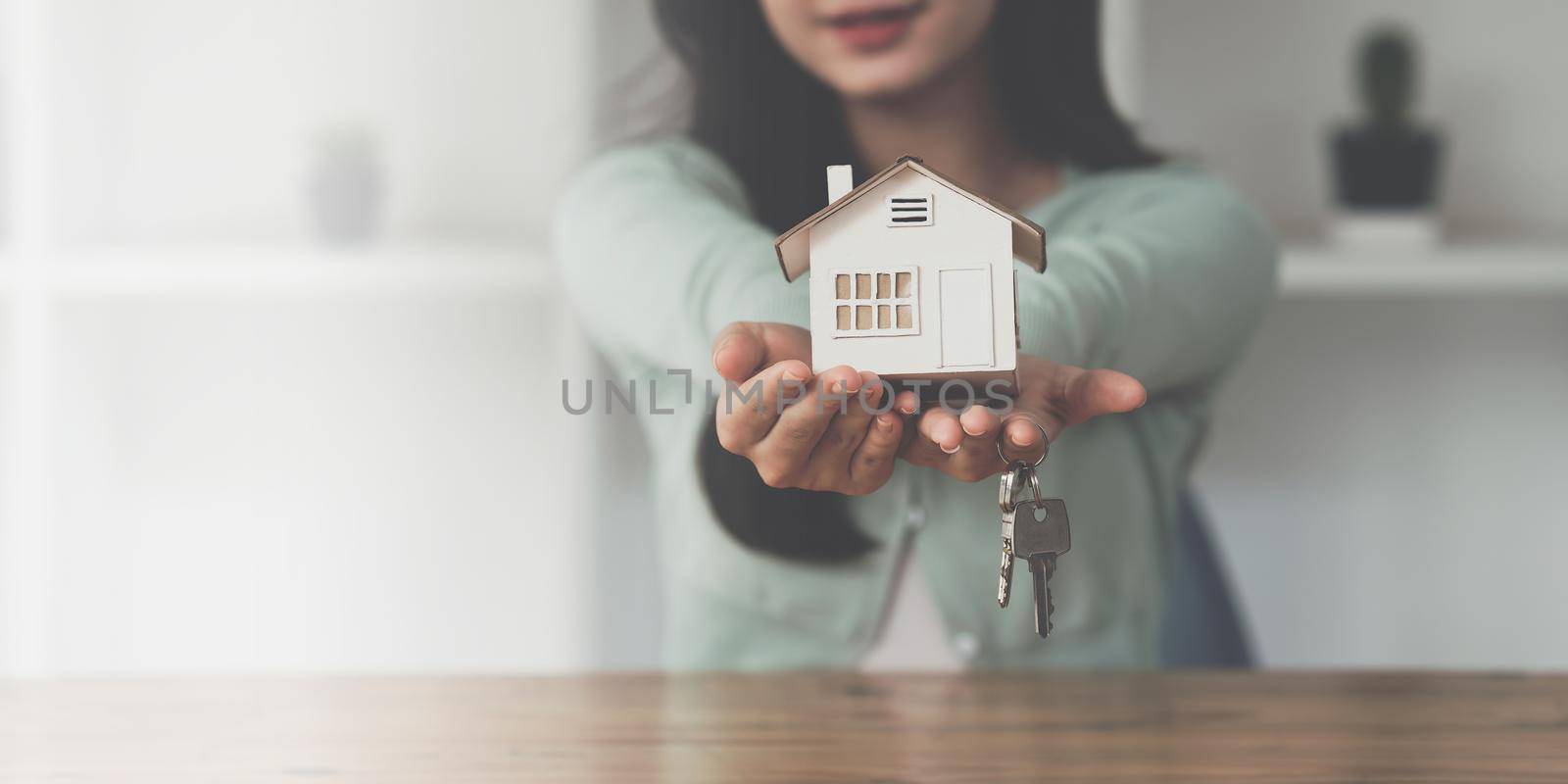 Close up Business woman or Real Estate agent giving house key after signing agreement for buying house. Bank manager and real estate concept. by itchaznong