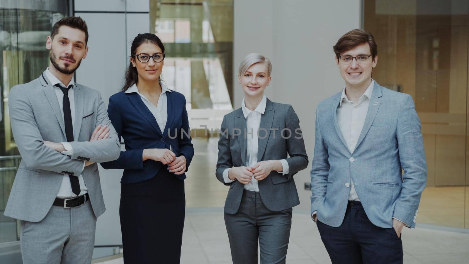 Portrait of group of business people smiling in modern office indoors. Team of businessmen and businesswomen standing together