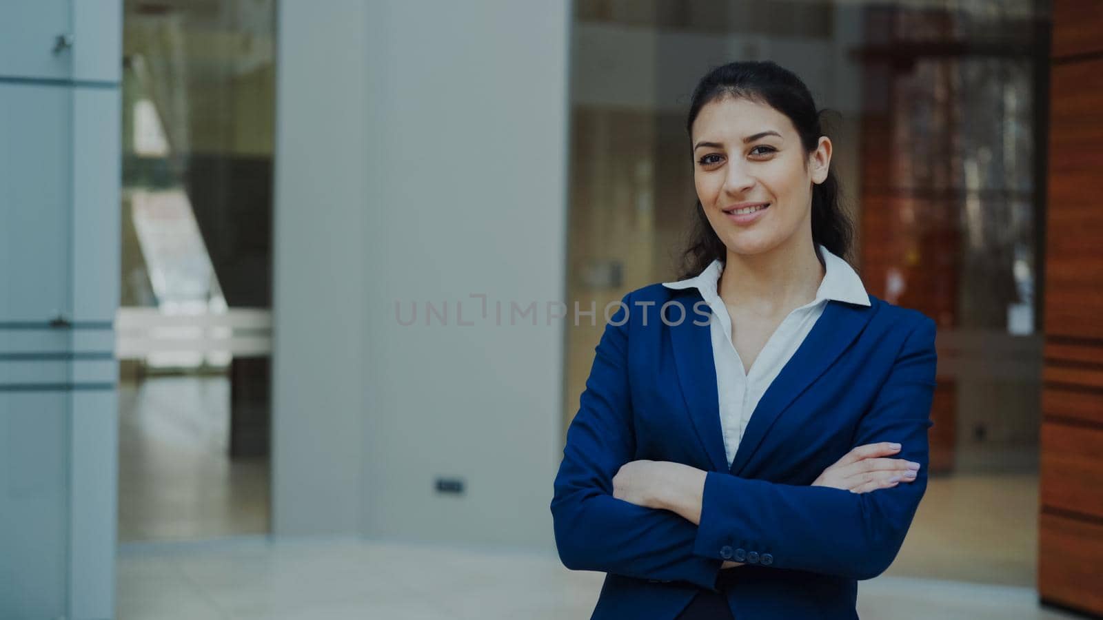Portrait of successful businesswoman smiling and looking into camera in modern office by silverkblack