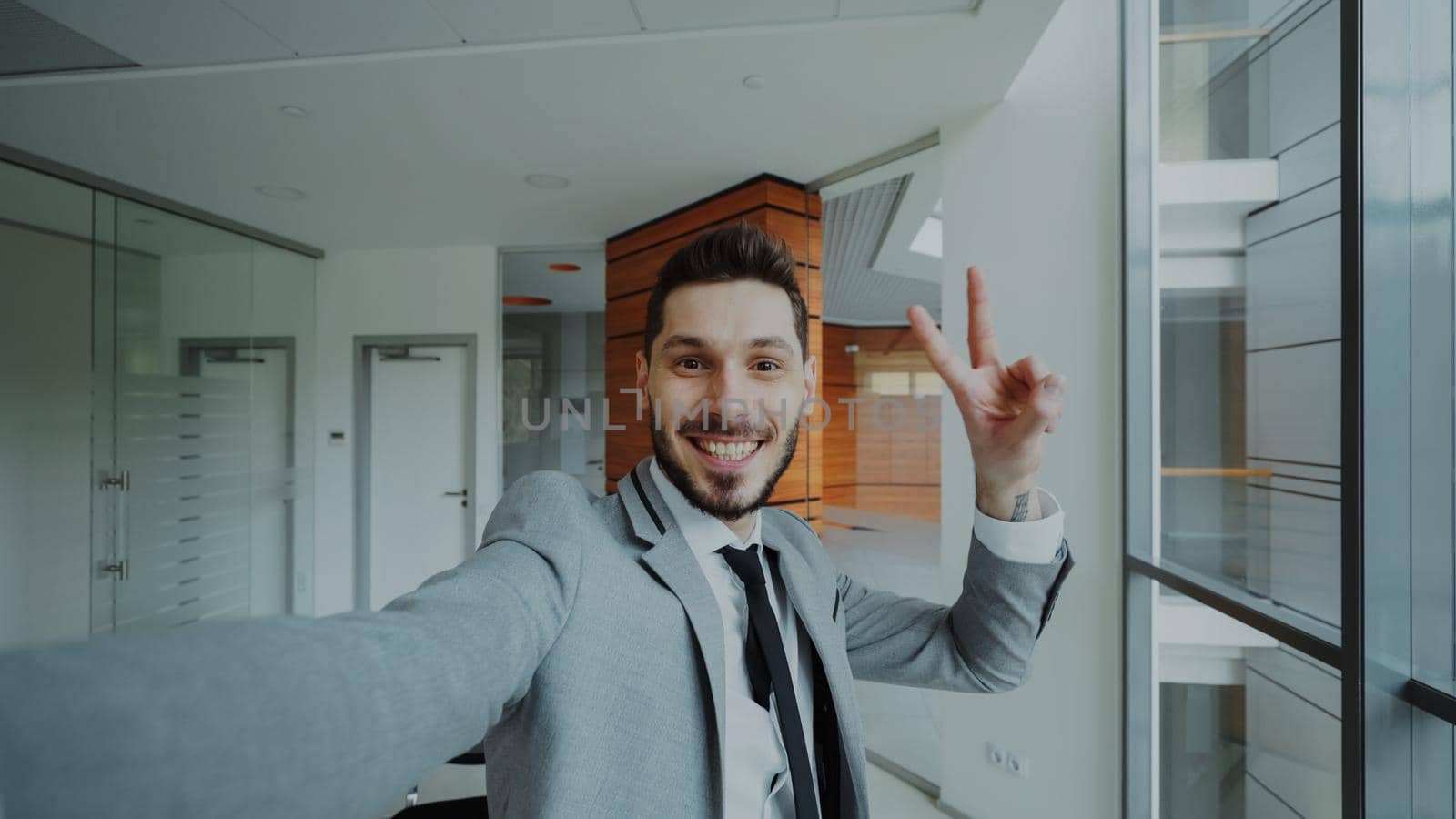 POV of young businessman in suit taking a selfie photo and have fun in modern office by silverkblack