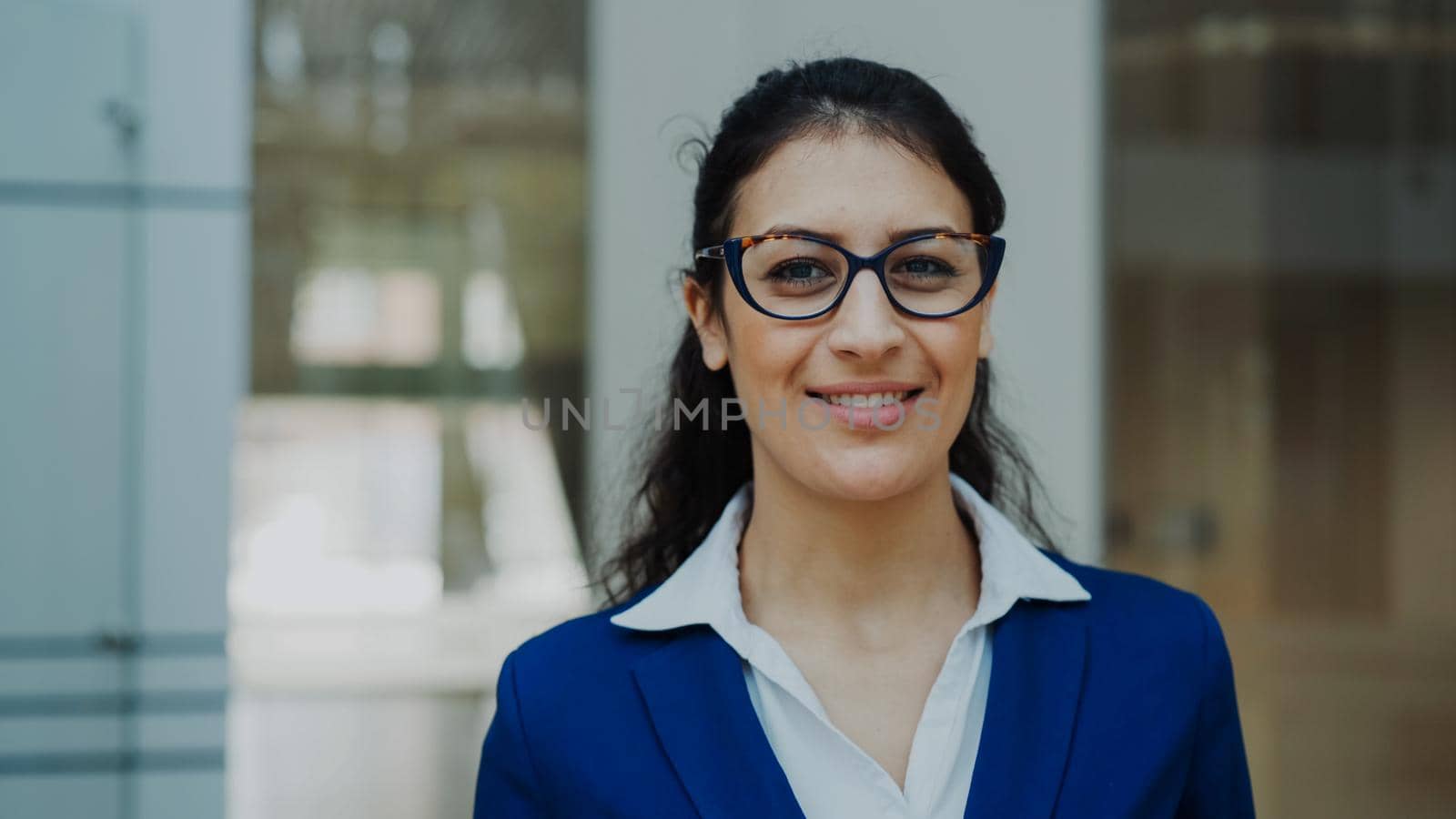 Portrait of successful businesswoman in glasses smiling in modern office indoors