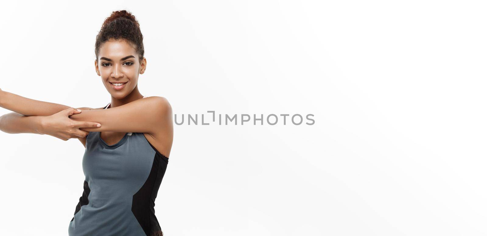 Sport, training, lifestyle and Fitness concept - portrait of beautiful happy African American woman stretching hands. Isolated on white studio background