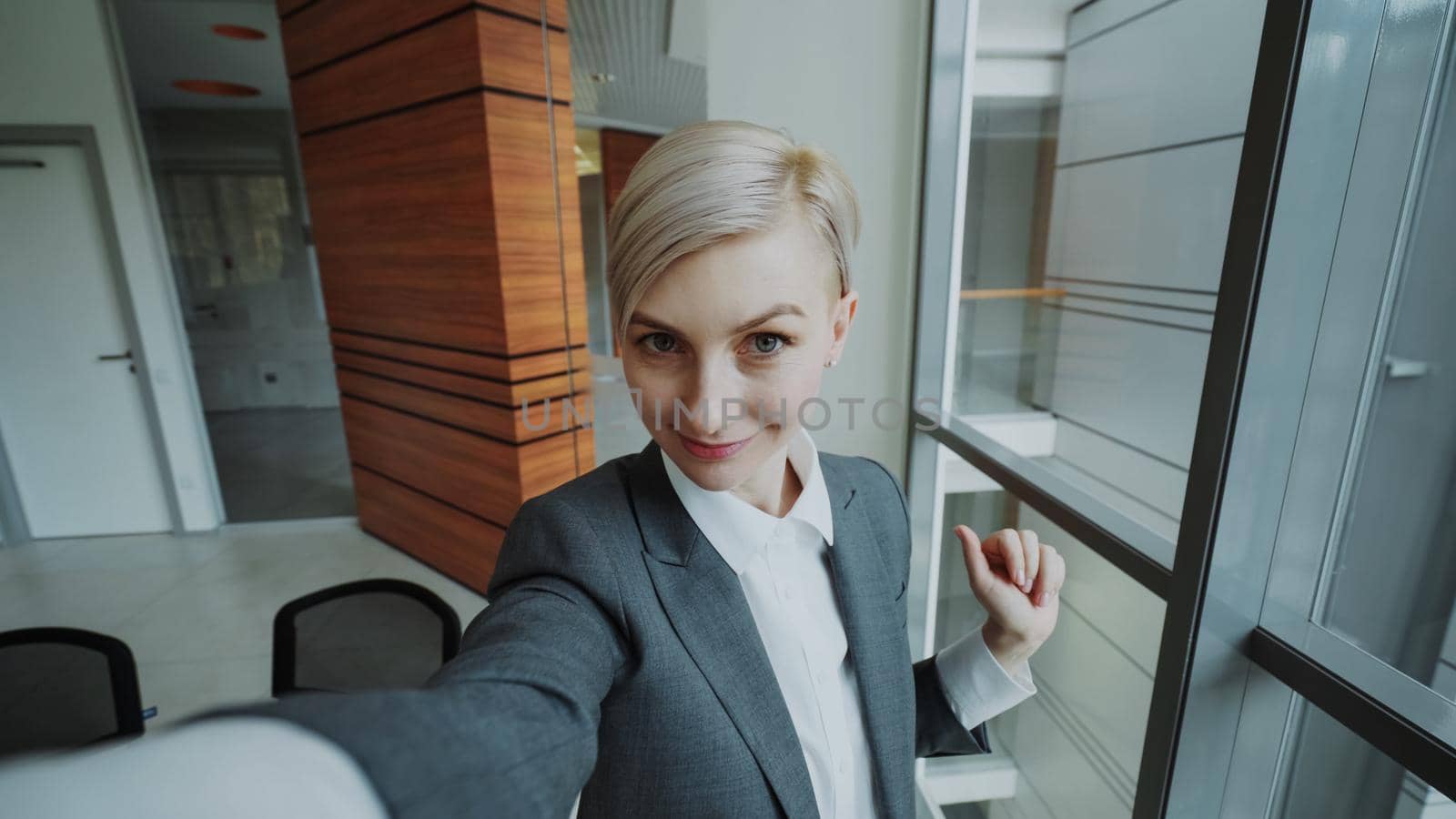 POV of young businesswoman in suit taking a selfie photo holding smartphone and have fun in modern office by silverkblack