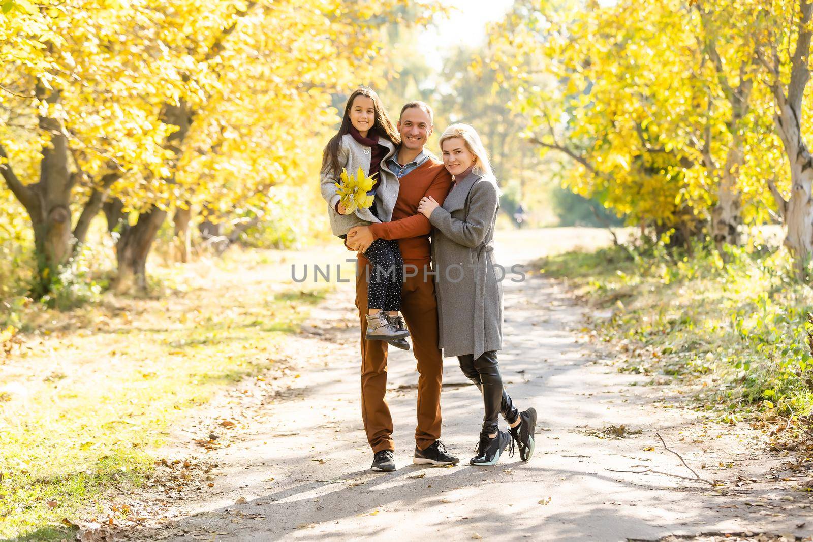 Young happy family while walking in the autumn park