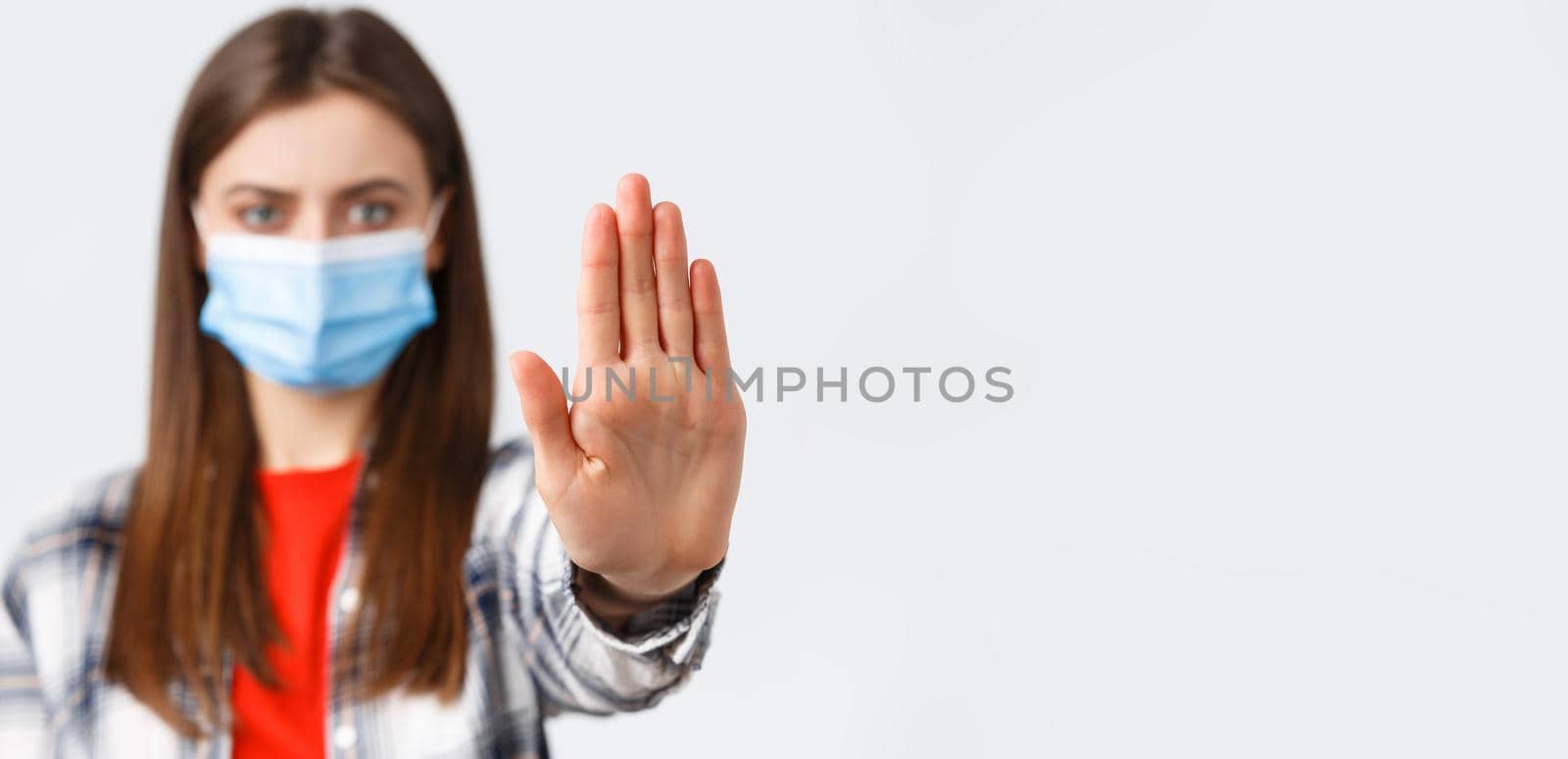 Coronavirus outbreak, leisure on quarantine, social distancing and emotions concept. Close-up of serious woman stretch palm to say stop, restrict or prohibit from bad decisions, wear medical mask.