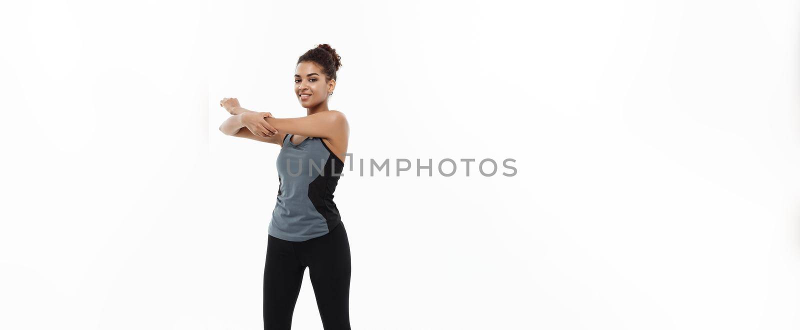 Sport, training, lifestyle and Fitness concept - Full-length portrait of beautiful happy African American woman stretching hands. Isolated on white studio background