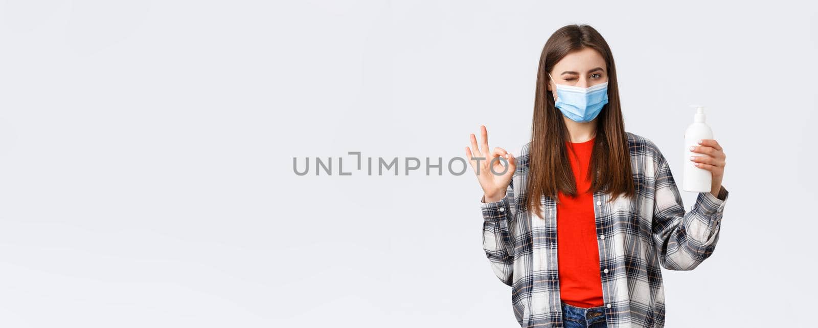 Coronavirus outbreak, leisure on quarantine, social distancing and emotions concept. Cute caucasian woman in medical mask assure this soap is good for preventing virus, show oka sign.