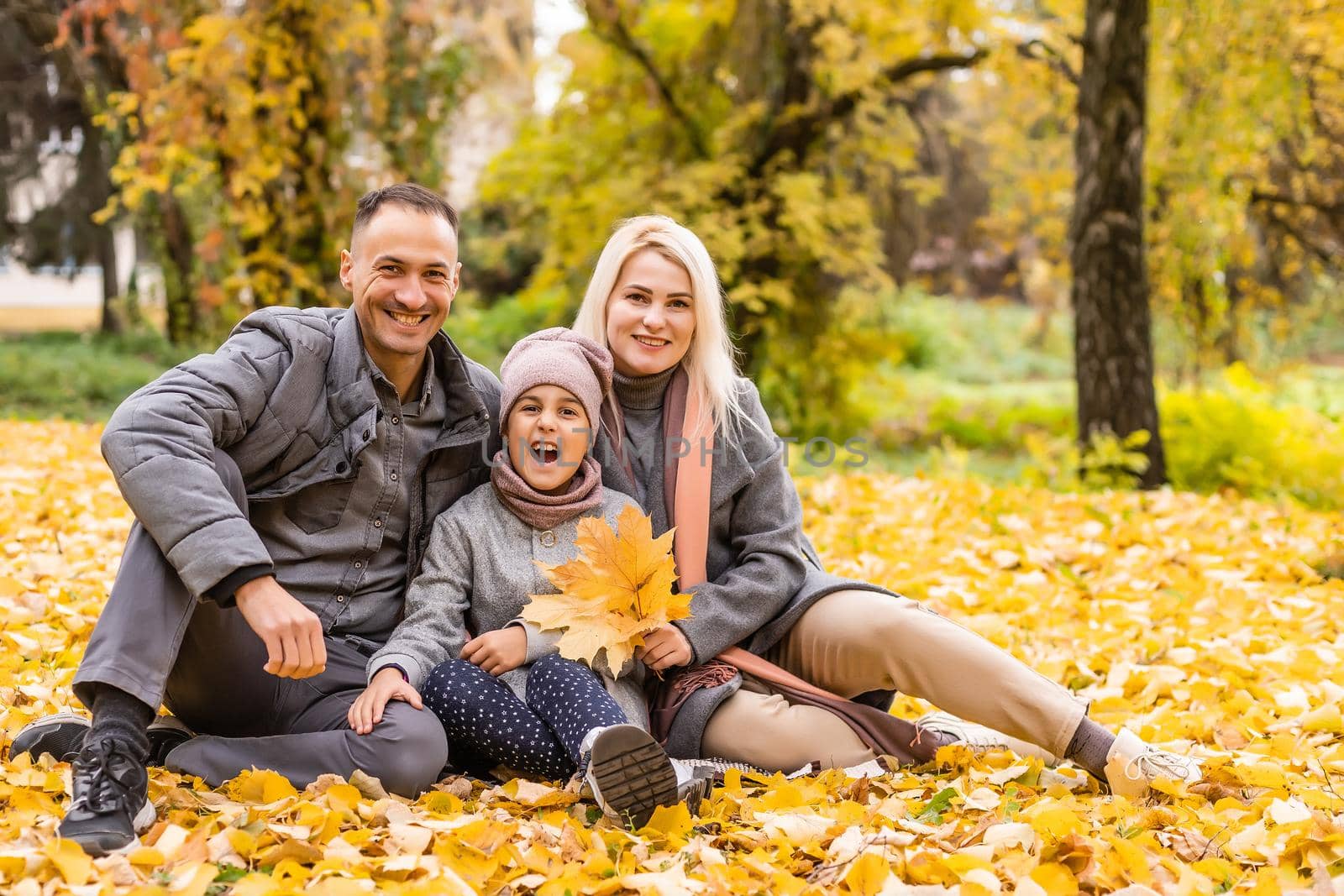A Family of four enjoying golden leaves in autumn park.