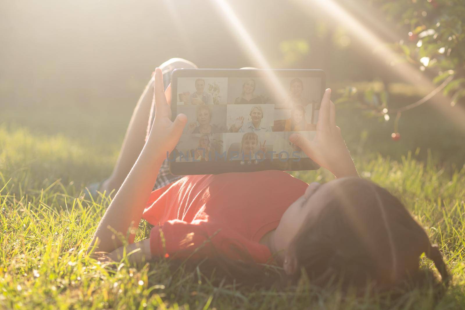 Girl on the grass with a tablet chat in her hands in the garden.