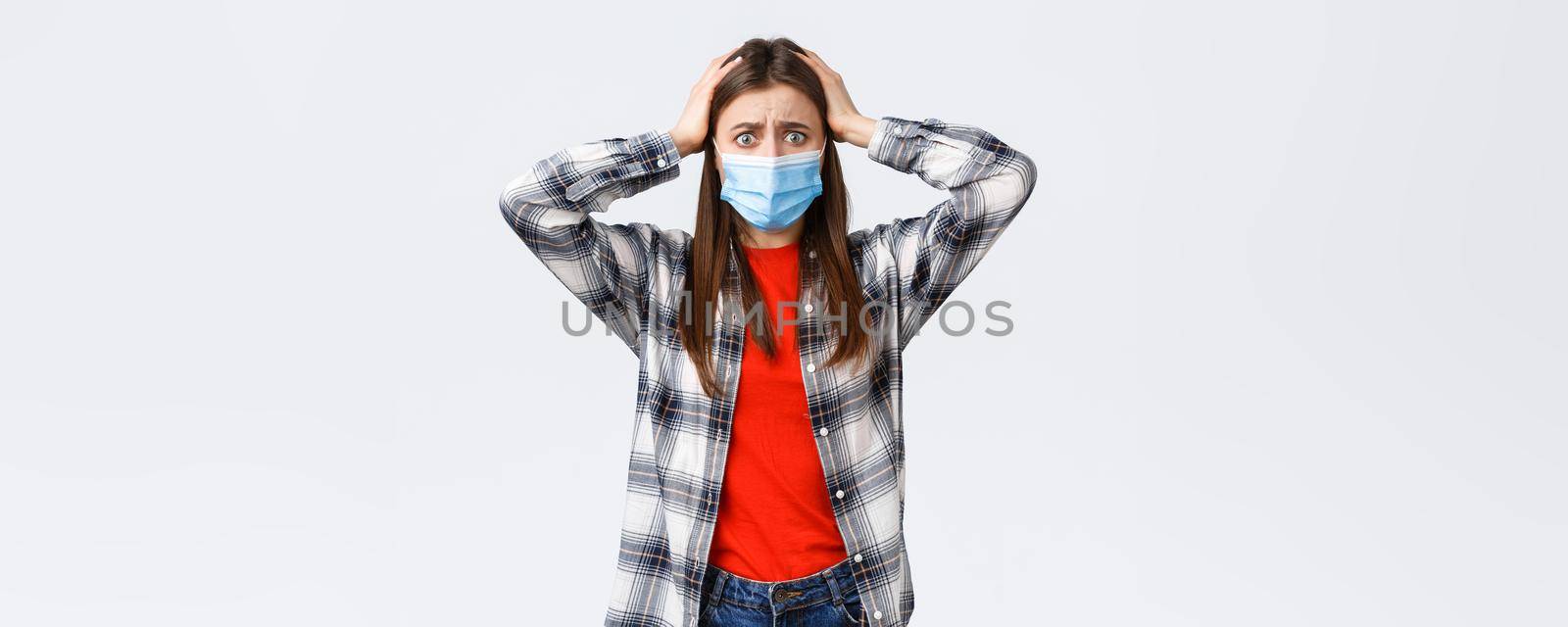 Different emotions, covid-19 pandemic, coronavirus self-quarantine and social distancing concept. Alarmed and worried, panicking young woman in medical mask, grab head indecisive, feel scared by Benzoix