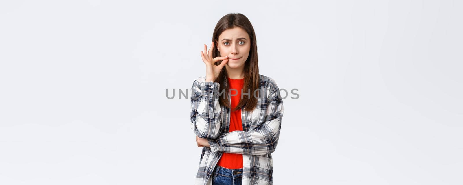 Lifestyle, different emotions, leisure activities concept. Serious-looking young woman promise keep mouth shut, making seal lips gesture, zipping it and look camera, someone sharing secret.