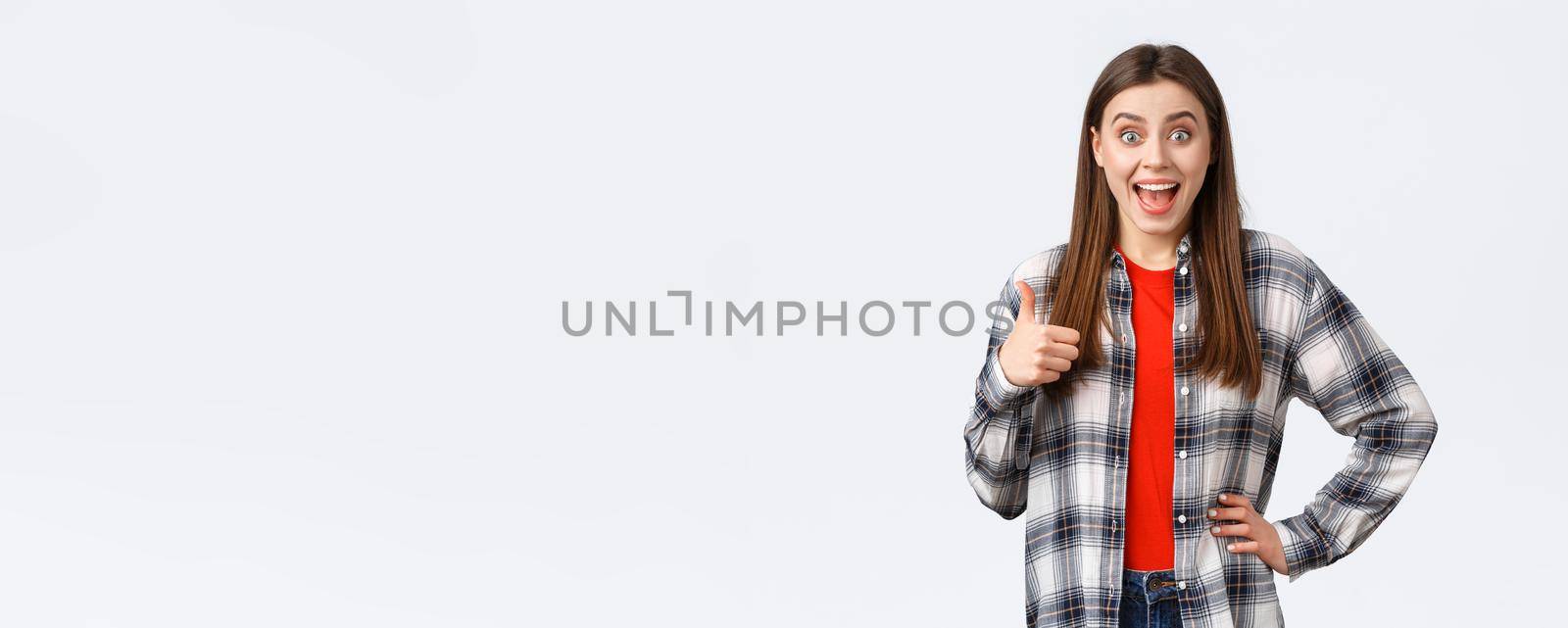 Lifestyle, different emotions, leisure activities concept. Surprised and excited cheerful girl support great idea, show thumb-up and smiling amazed, approva and like plan, white background.