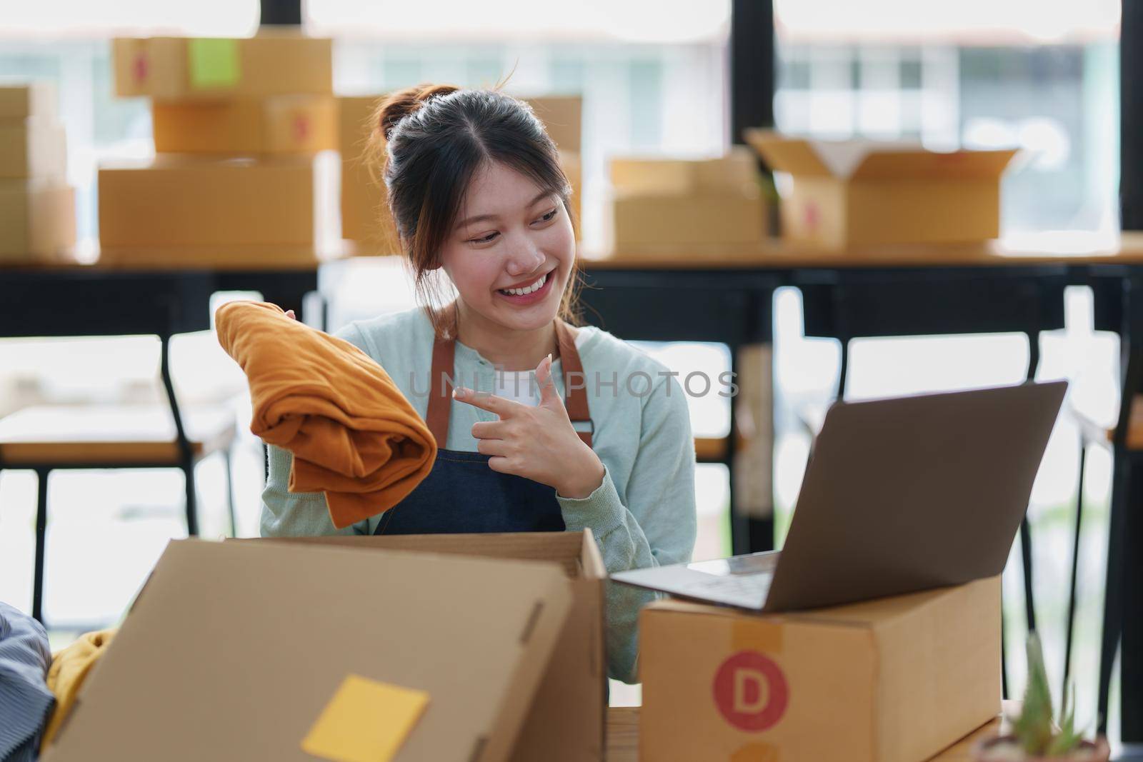 Image of Young asian woman startup freelance with product and showing to customer by computer laptop. Online marketing packing box delivery concept. by itchaznong
