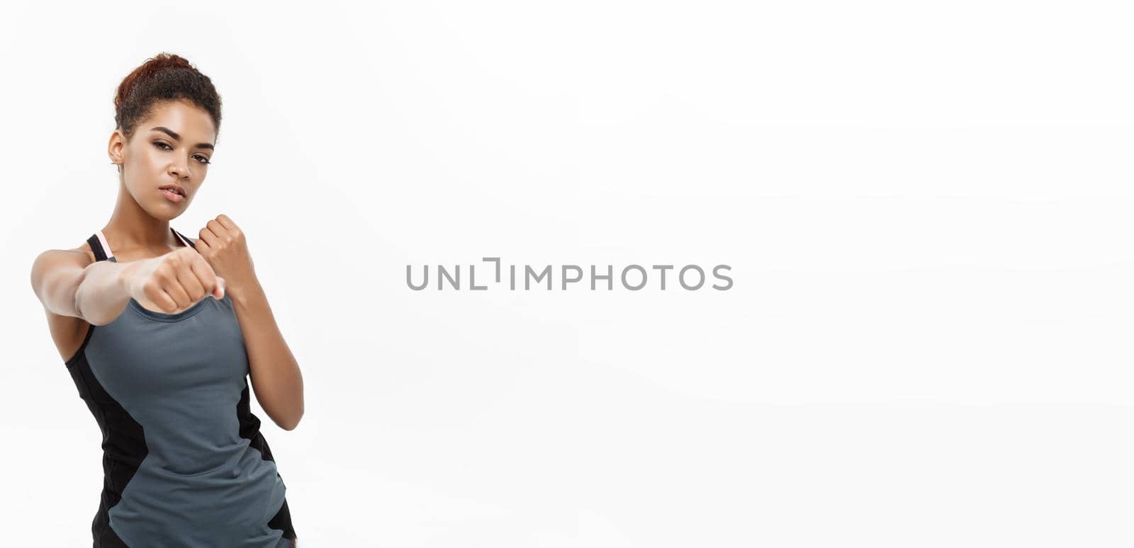 Healthy and Fitness concept - portrait of African American woman punching in air with confident face. Isolated on white background