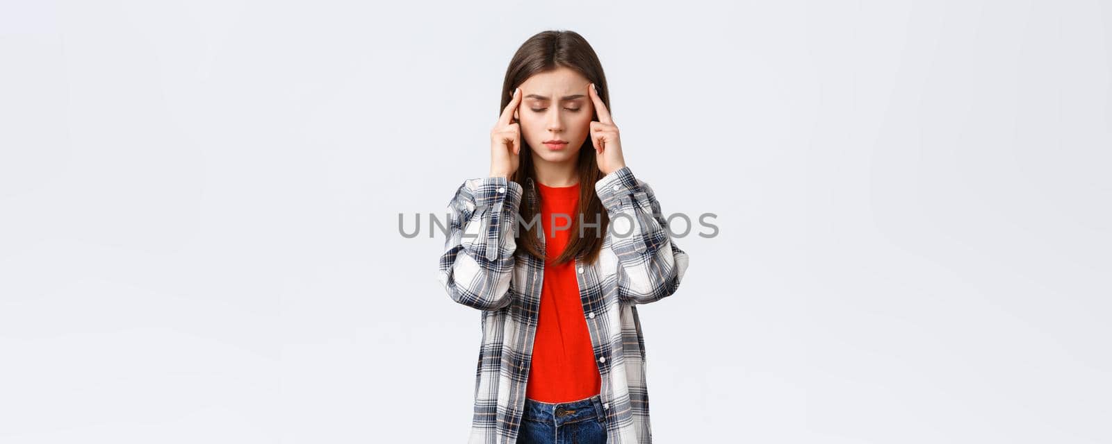Lifestyle, different emotions, leisure activities concept. Distressed and exhausted young female student trying focus, feel headache or dizzy, close eyes and rub temples, white background by Benzoix