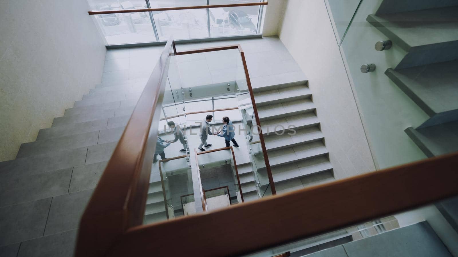 Top view of two businessmen meet at stairs in modern office center and talking while having break by silverkblack