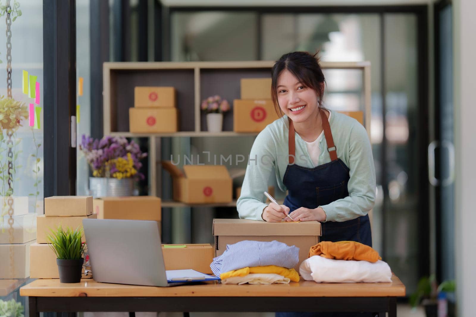Image of Young asian woman startup freelance with parcel box and talking with customer by computer laptop. Online marketing packing box delivery concept. by itchaznong