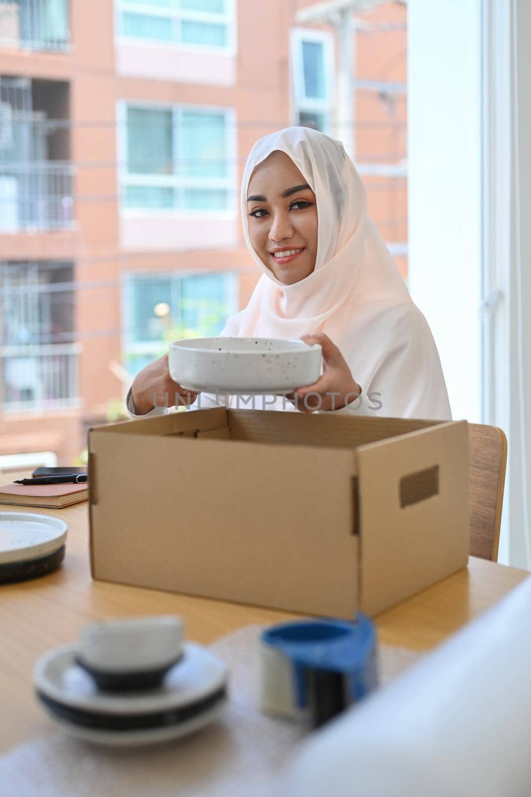 Beautiful Muslim woman in hijab preparing parcel boxes of product for shipping to customers.