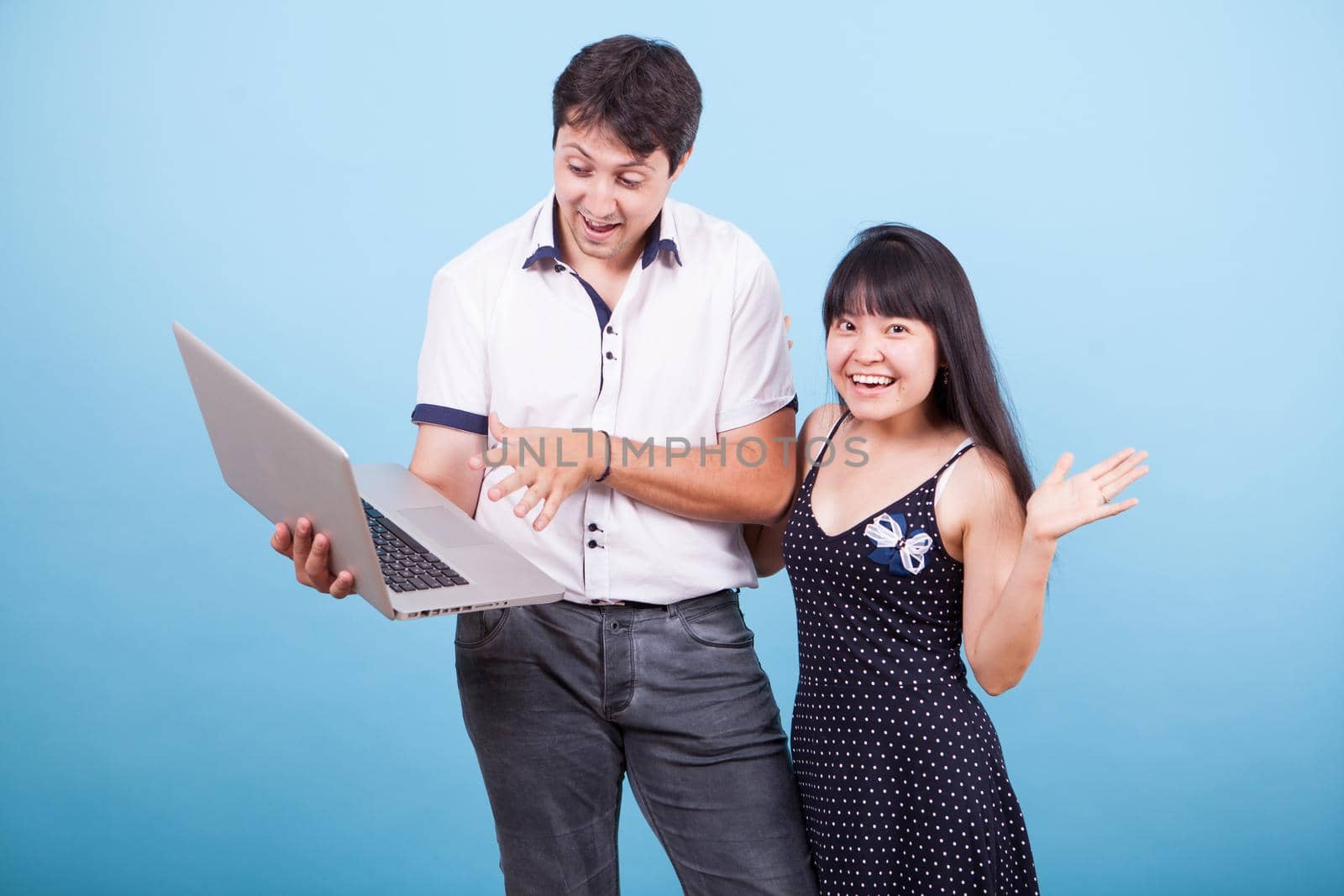 Caucasian husband showing his asian wife something exciting on laptop by DCStudio