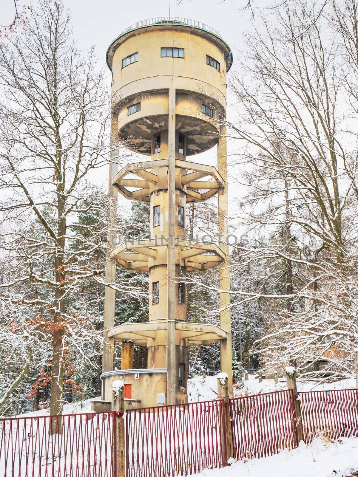 Water tower in a snowy forest park at field against a cloudy sky by rdonar2