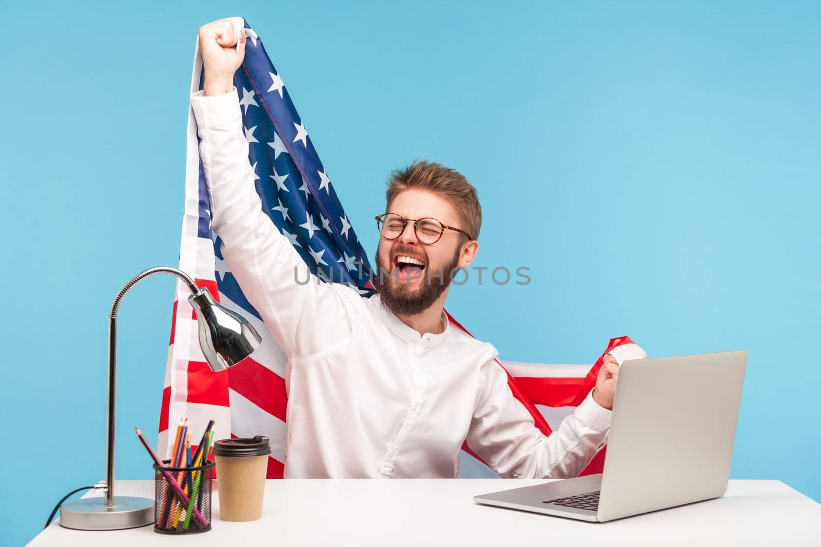 Extremely happy businessman raising American flag and yelling crazy for joy in office workplace, celebrating labor day or US Independence day 4th of july, government employment support. studio shot