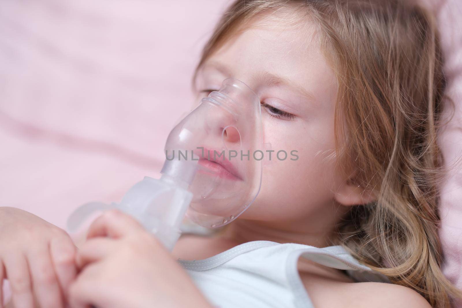 Little caucasian girl makes inhalation and breathes with special mask. Asthma attack or relieve symptoms of respiratory disease concept