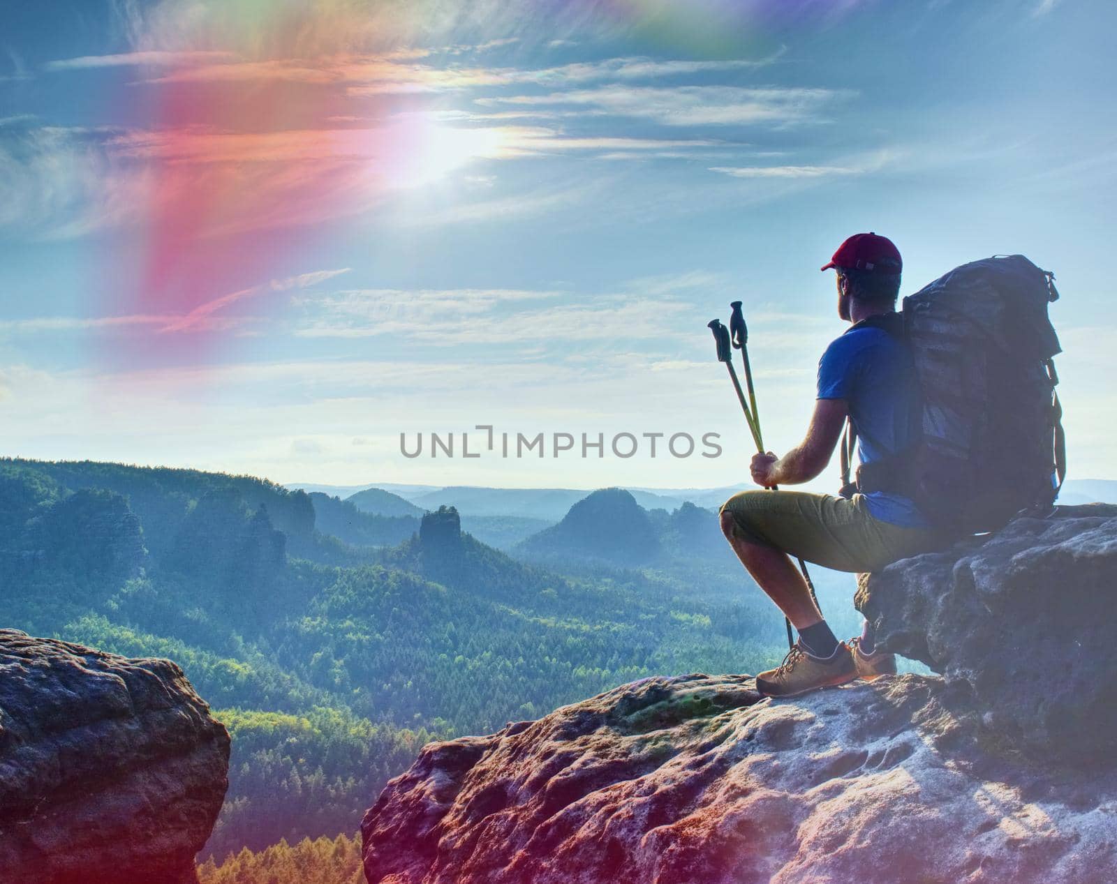 Man sitting on the rock cliff in mountain and watching sunrise by rdonar2