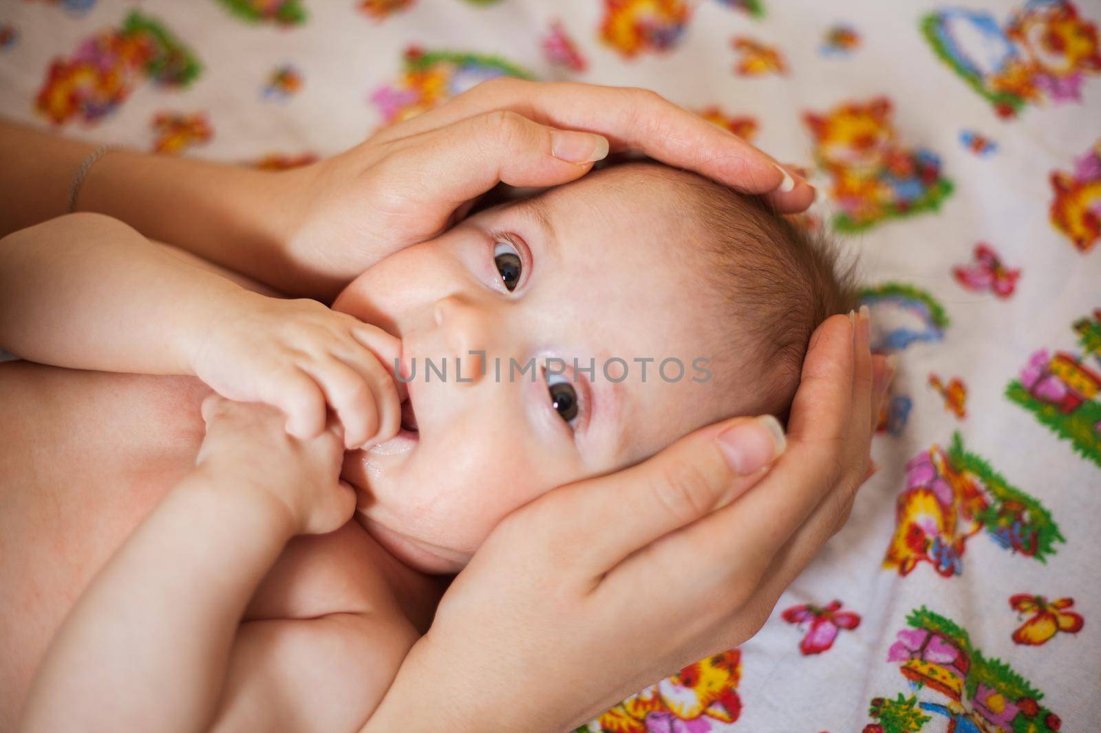 Mother holding head of her newborn daugther in hands by InnaVlasova