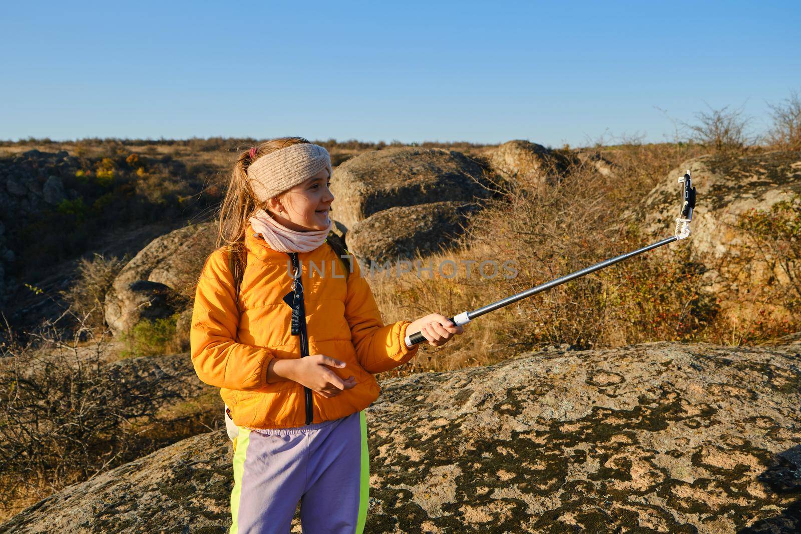 Shot of a kid girl talking on camera in hills, make video blog use device make video hold hand social network blog. child vlogger filming video diary outdoors. kid creating social media content.