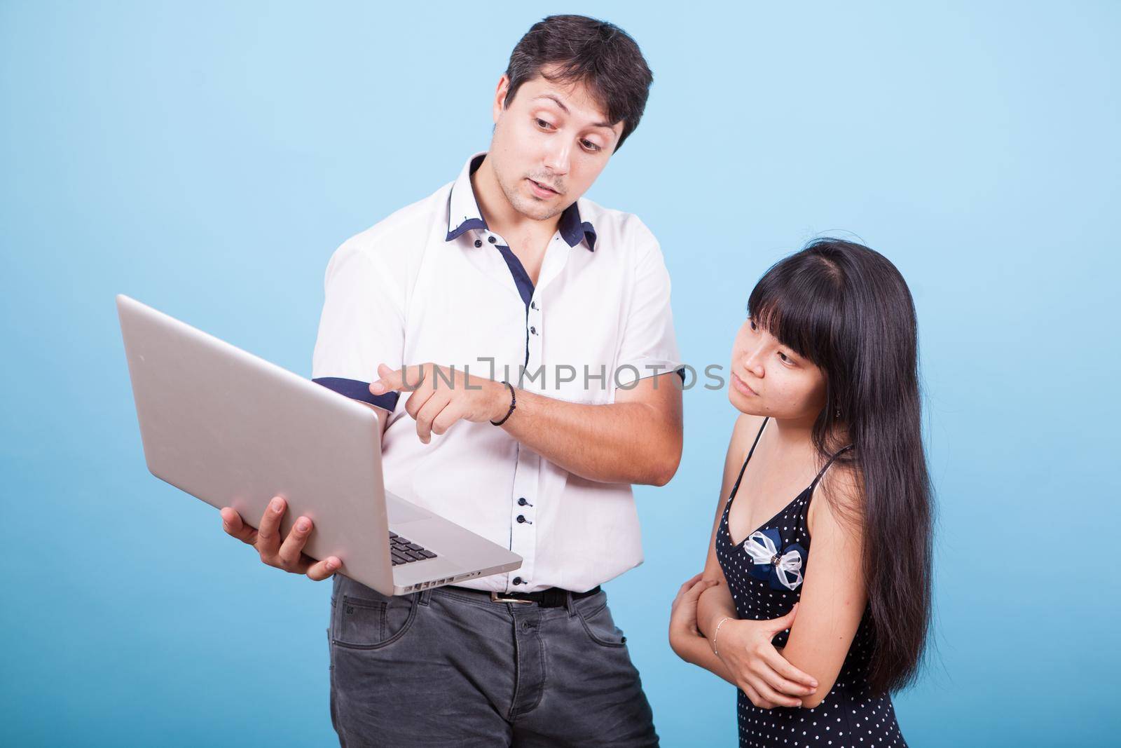 Caucasian male pointing at laptop and consulting with his asian wife. Interracial couple.