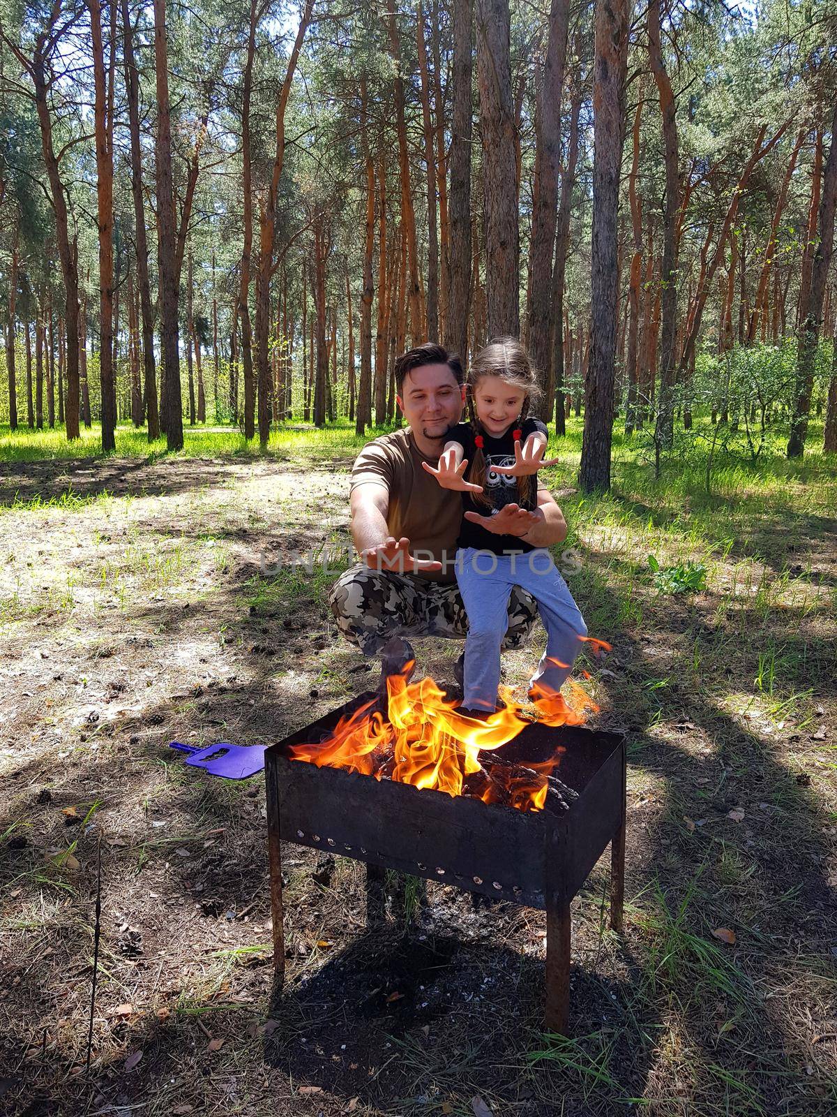 Father and daughter making barbecue grilling on metal skewer. Meat roasting at barbecue. BBQ fresh beef chop slices. Traditional eastern dish. Grill on charcoal and flame, picnic, street food