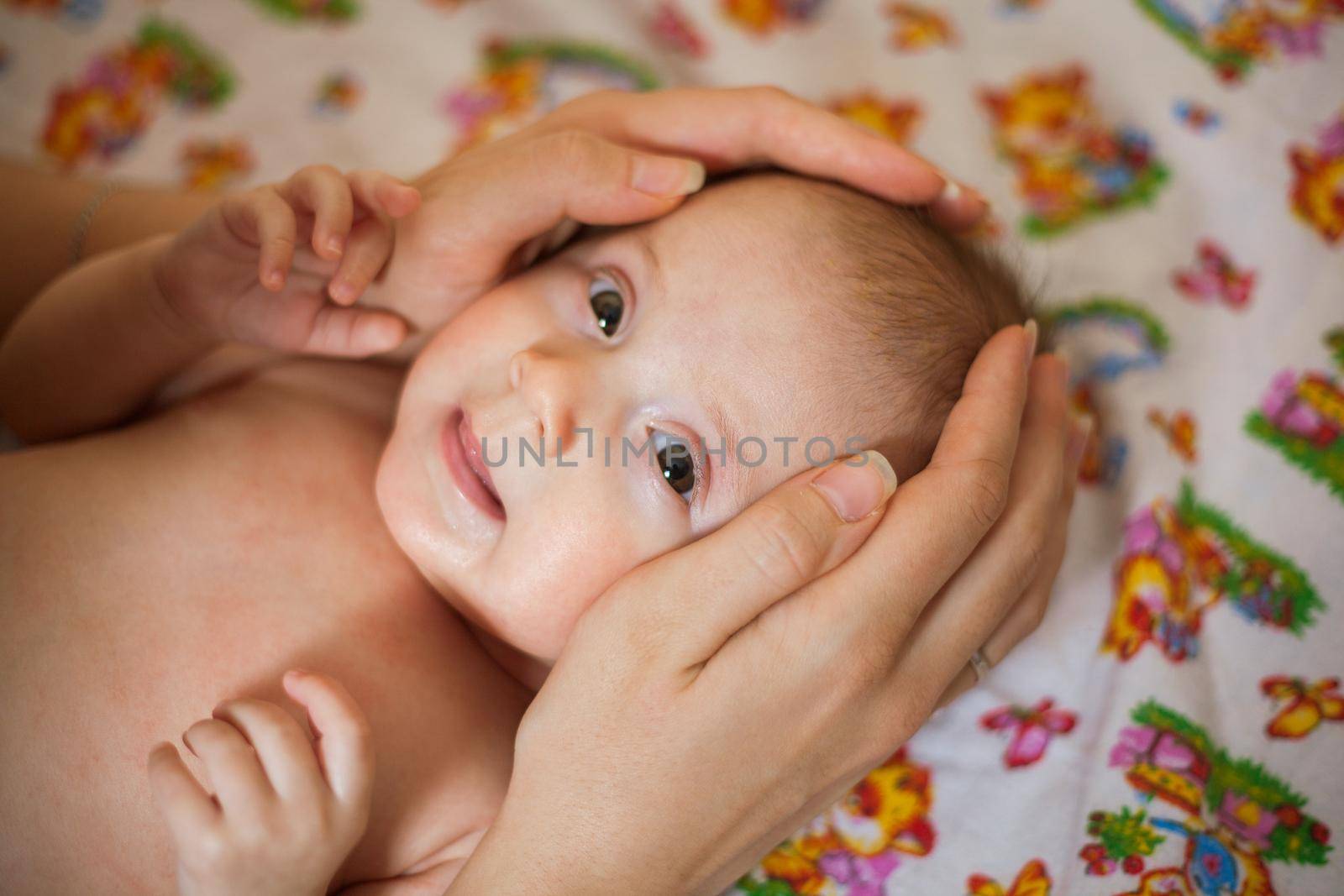 Mother holding head of her newborn daugther in hands. The baby on hands at mum. Loving mother hand holding cute smiling newborn baby child