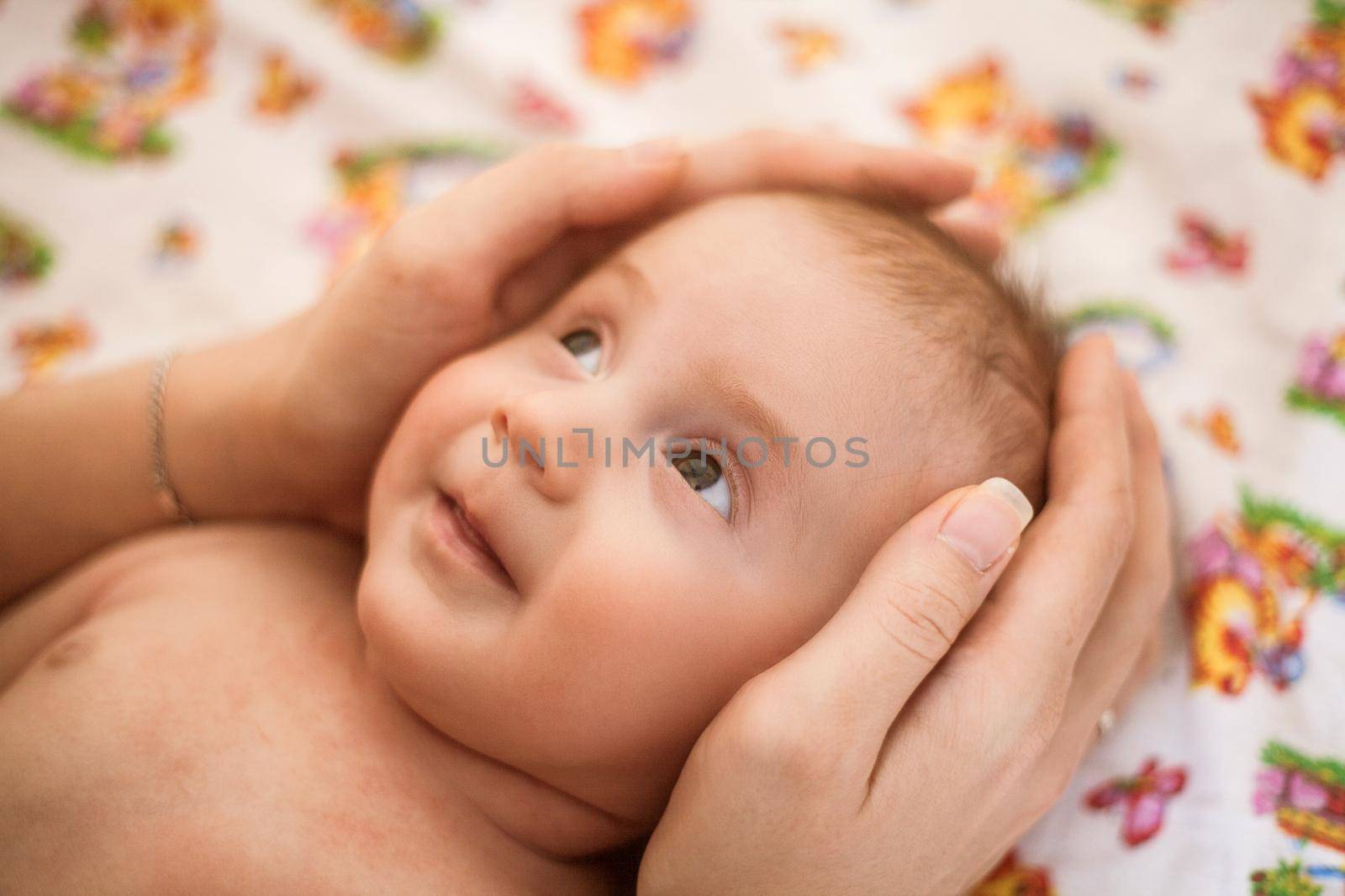 Mother holding head of her newborn daugther in hands. The baby on hands at mum. Loving mother hand holding cute smiling newborn baby child