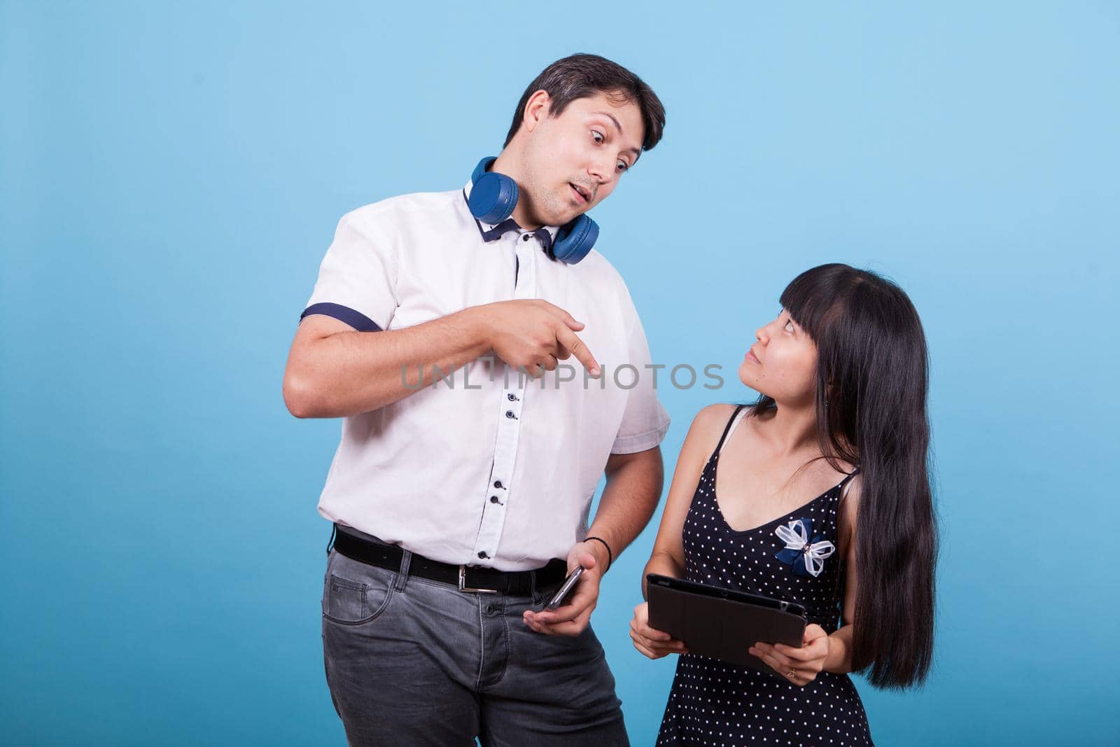 Caucasian boyfriend pointing at table and asian girlfiend looking at him by DCStudio