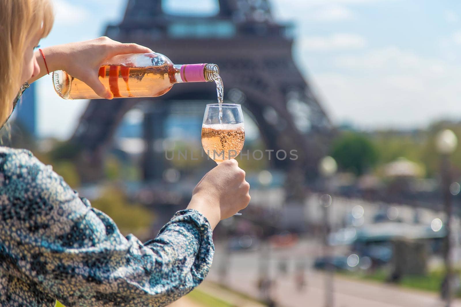 A woman pours wine near the Eiffel Tower. Selective focus. by yanadjana