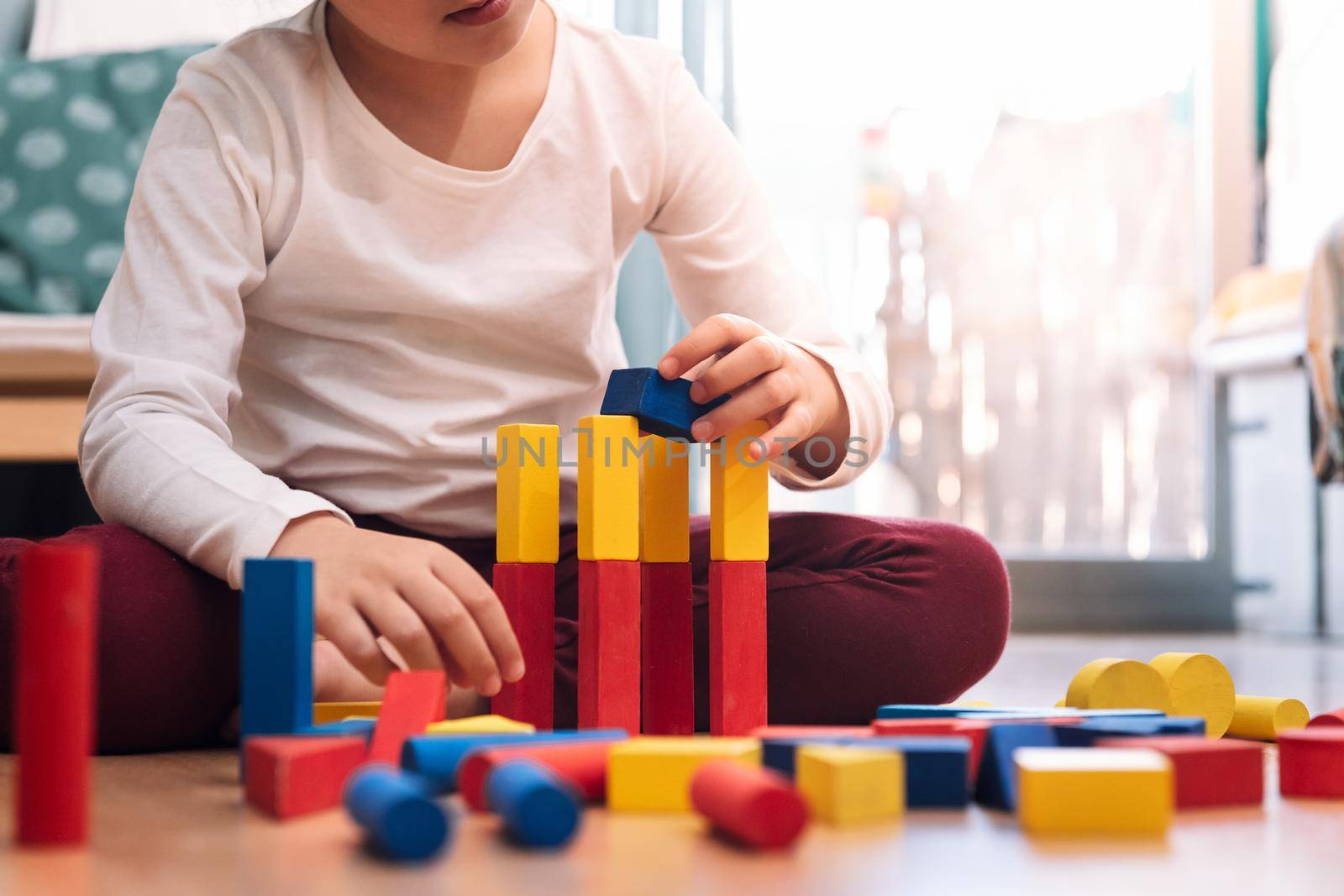 unrecognizable kid playing at home with building blocks, concept of indoor leisure for children