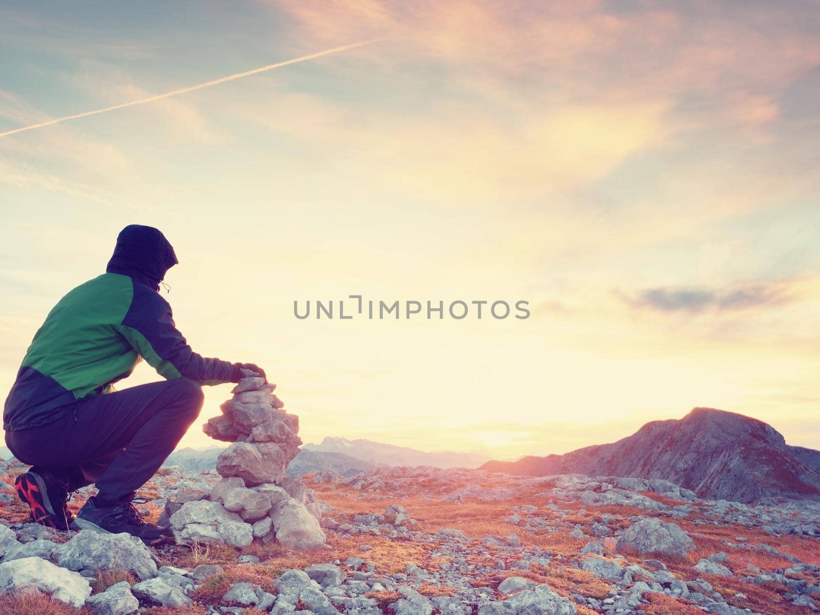 Man put the last stone intopeak of  pyramid. Balanced stone pyramid on  mountain summit. by rdonar2