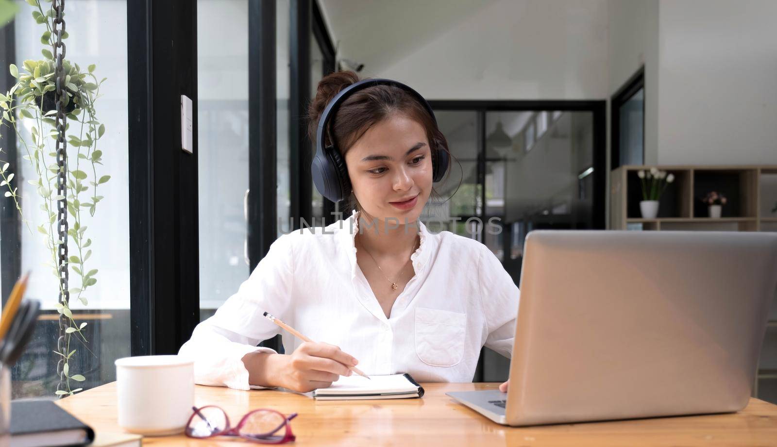 asian woman interpreter write translation from foreign language to english listen to audio record in headset. .