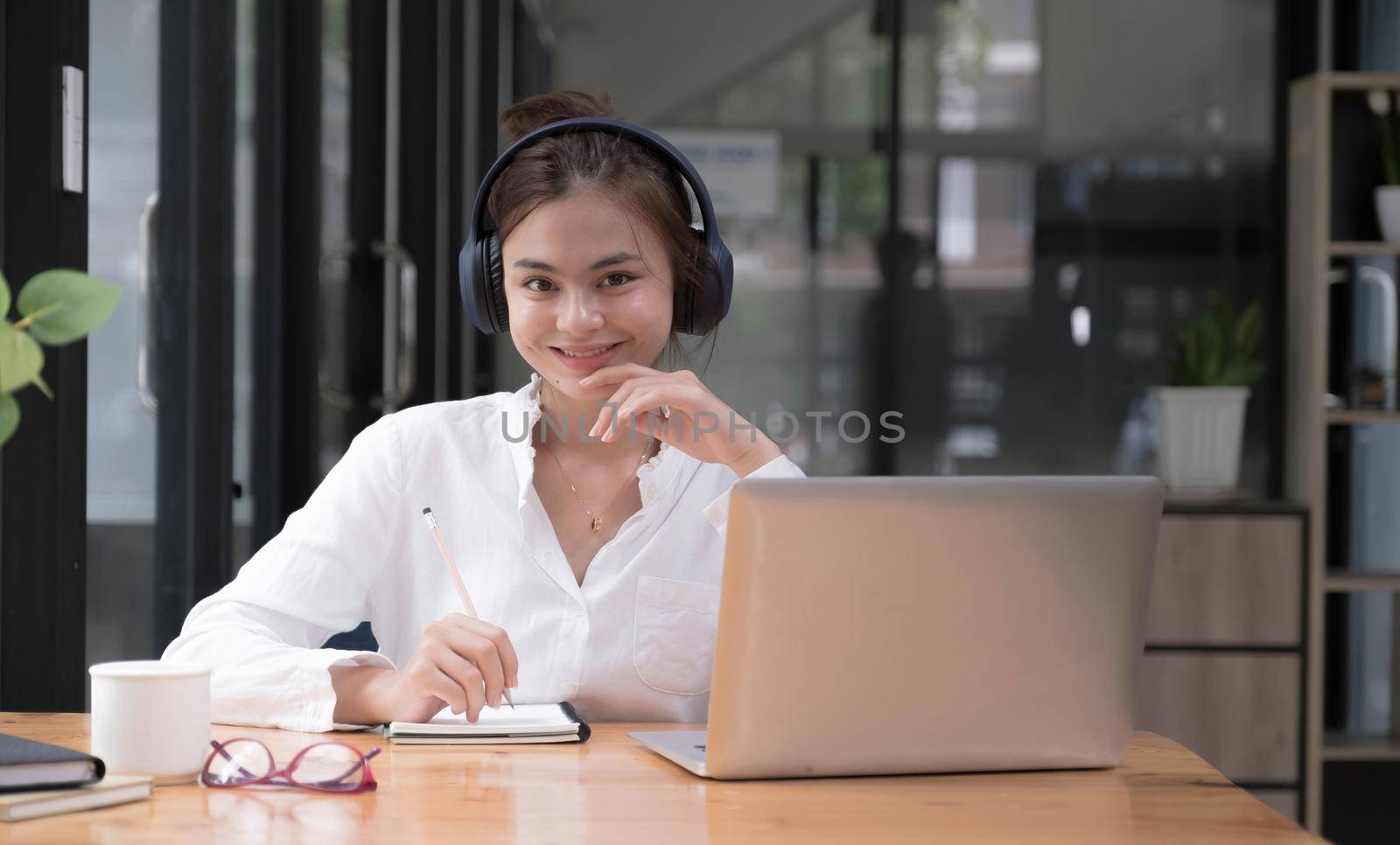 girl practicing online Use a laptop and a wireless headset. looking at camera.
