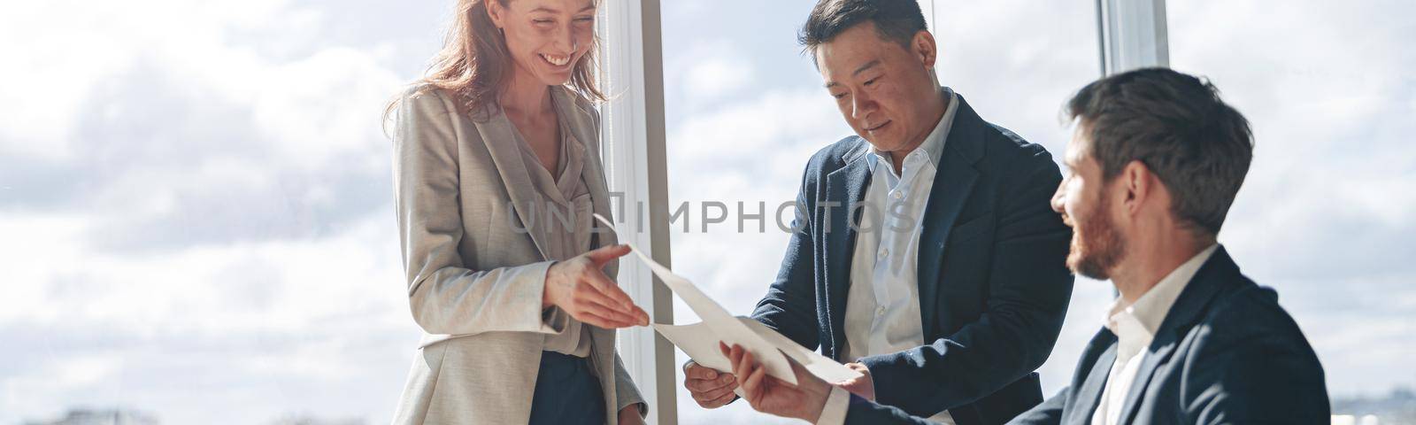 office employees discussing work issues using laptop and documents with charts in a modern office