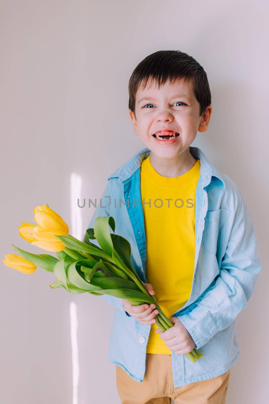 A boy with a bouquet of tulips lifestyle . Postcard for March 8. Congratulations on Women's Day. Congratulations on Mother's Day. Flowers are tulips. by alenka2194
