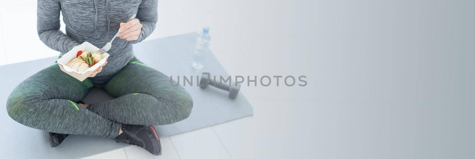 sport, healthy, people concept - Girl holding salad and dumbbell after fitness training.