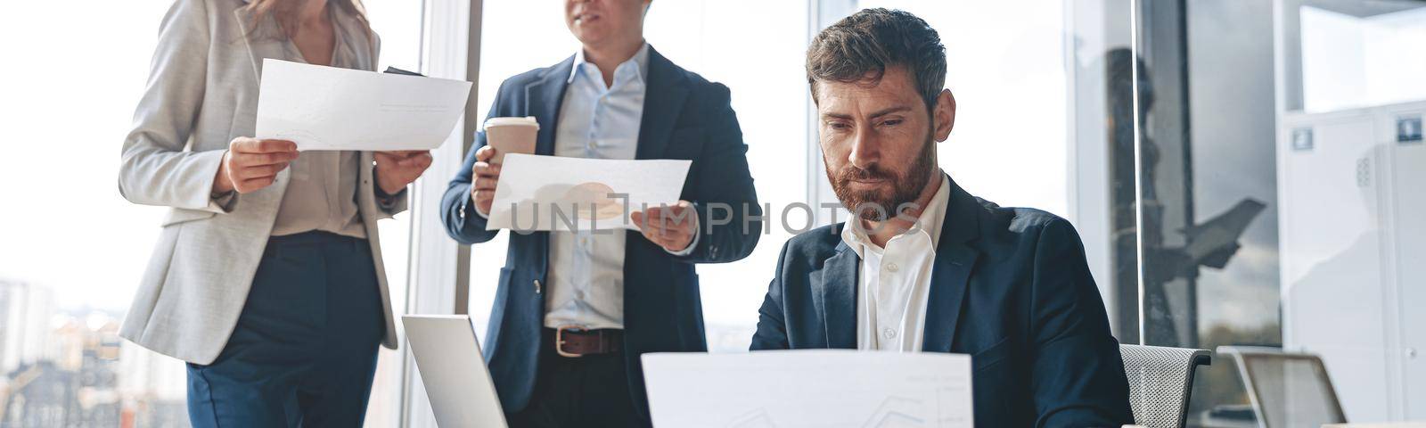Smiling businessmen discussing documents with graphs and charts in a modern office during meeting by Yaroslav_astakhov