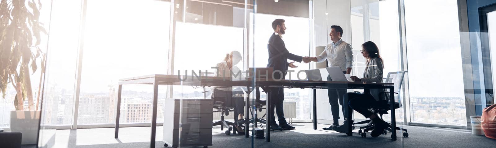 Team of young businessmen working and communicating together in office. Blurred background