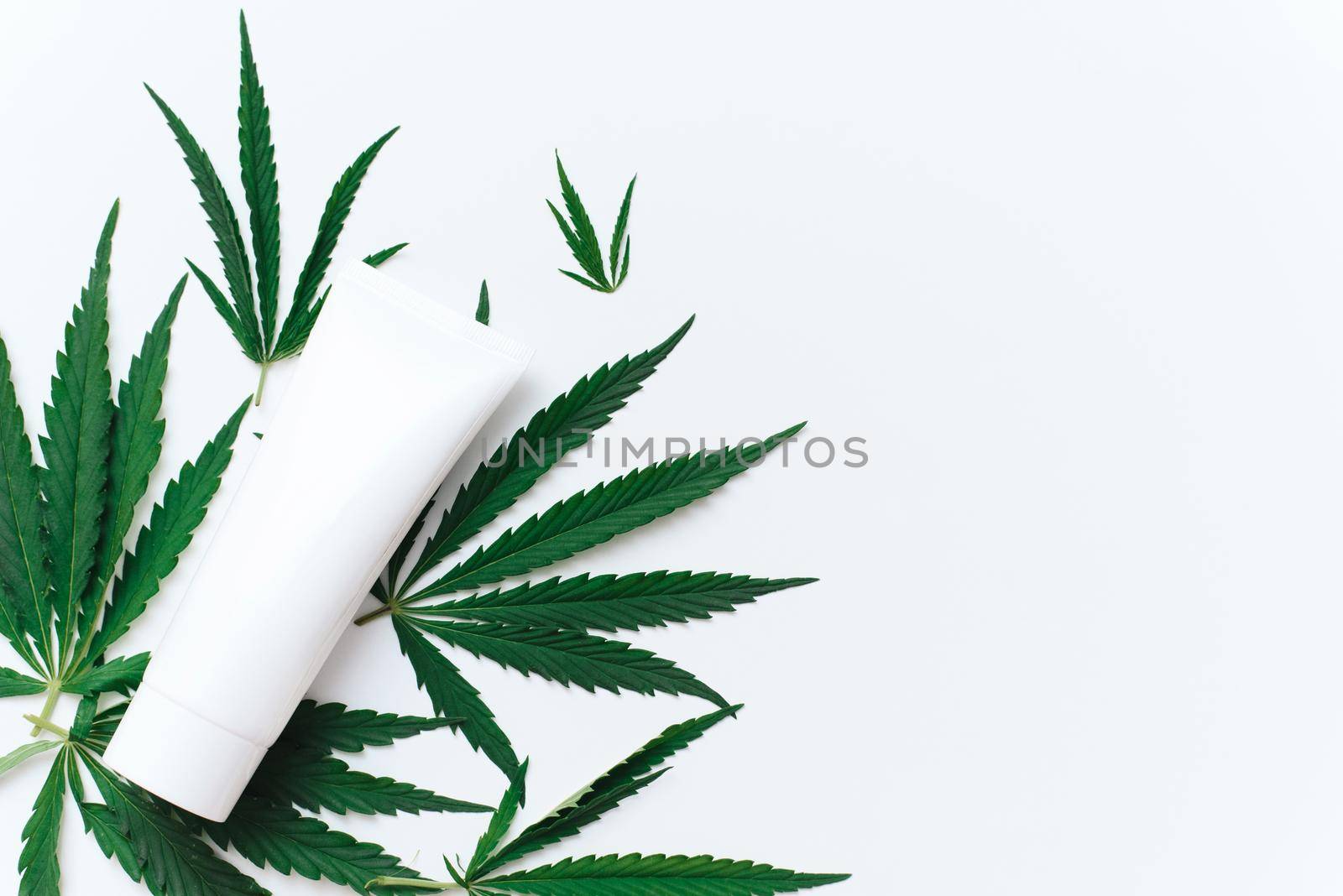 Tube with hemp oil moisturizer on white background with copy space and mockup. Cannabis in the production of cosmetics for skin care.