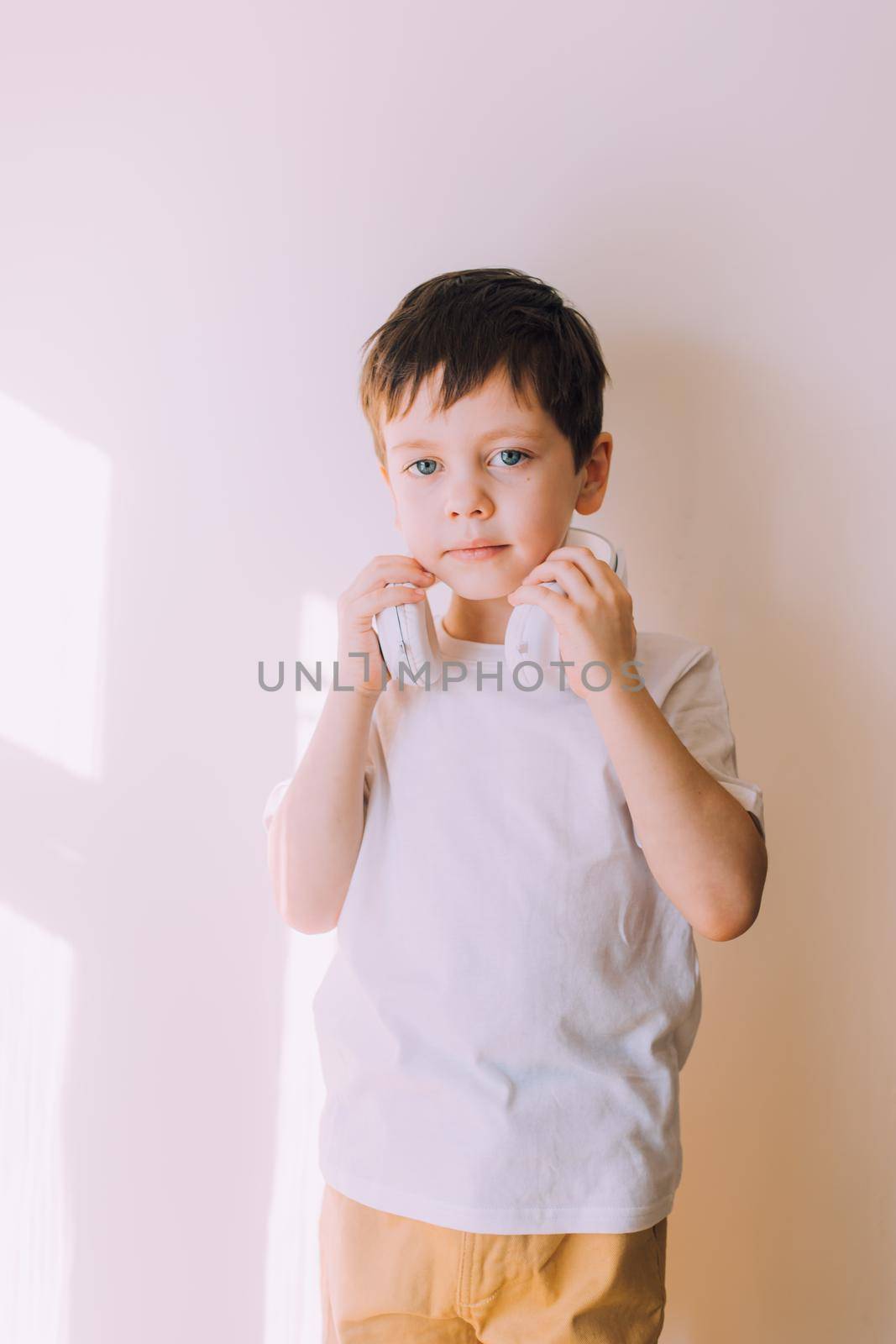 The boy listens to music with lifestyle headphones . Modern technologies. Kids and gadgets. Music for children. Modern children. Smartphones in children. Copy space. White background.