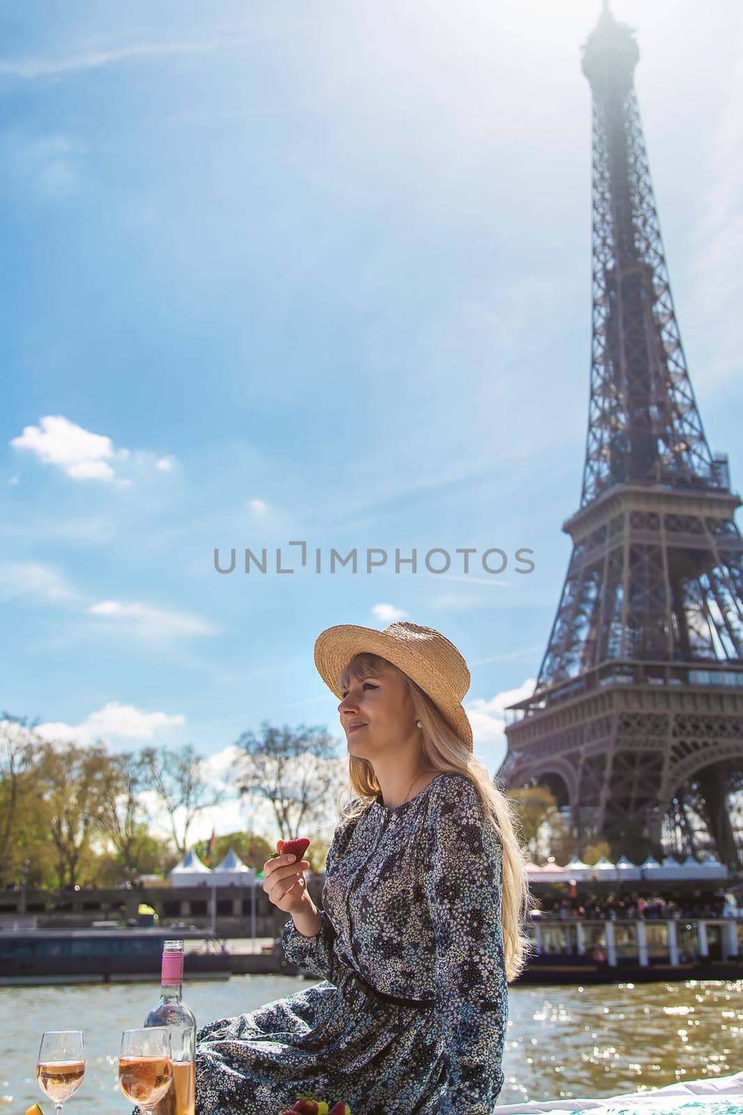 A woman near the Eiffel Tower drinks wine. Selective focus. People.