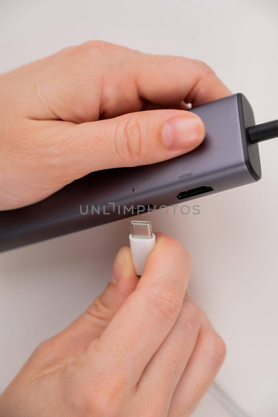 A woman inserts a white Type C cable into a black port. by mrwed54